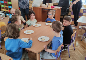 Zdjęcie przedstawia dzieci jedzące sernik