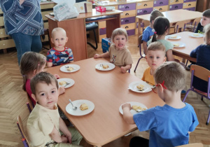 Zdjęcie przedstawia dzieci jedzące sernik