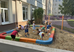 Zdjęcie przedstawia dzieci podczas zabaw w piaskownicy