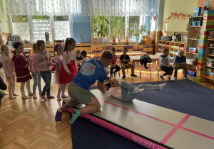 Zdjęcie przedstawia dzieci podczas zabaw akrobatycznych na macie