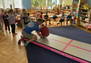 Zdjęcie przedstawia dzieci podczas zabaw akrobatycznych na macie