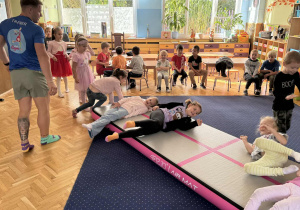 Zdjęcie przedstawia dzieci podczas zabaw akrobatycznych na macie