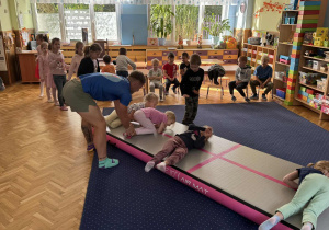 Zdjęcie przedstawia dzieci podczas zabaw akrobatycznych na macie