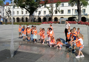 Zdjęcie przedstawia dzieci spacerujące po starym rynku w Łodzi