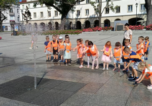 Zdjęcie przedstawia dzieci spacerujące po starym rynku w Łodzi