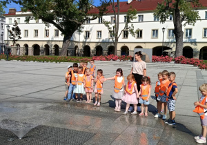 Zdjęcie przedstawia dzieci spacerujące po starym rynku w Łodzi