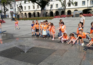 Zdjęcie przedstawia dzieci spacerujące po starym rynku w Łodzi