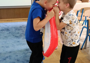 Zdjęcie przedstawia dzieci pompujące mini basenik