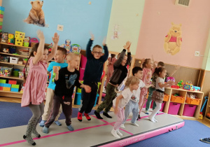 Zdjęcie przedstawia dzieci bawiące się na macie do akrobatyki