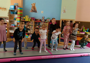 Zdjęcie przedstawia dzieci bawiące się na macie do akrobatyki