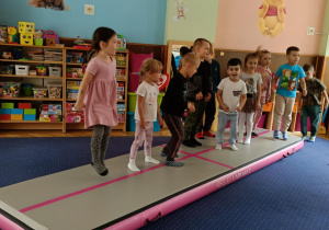 Zdjęcie przedstawia dzieci bawiące się na macie do akrobatyki