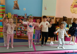 Zdjęcie przedstawia dzieci bawiące się na macie do akrobatyki