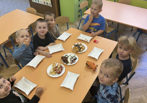 Zdjęcie przedstawia dzieci zajadające różne smakołyki