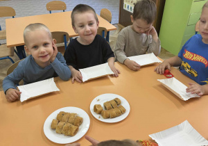 Zdjęcie przedstawia dzieci zajadające różne smakołyki