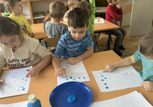 Zdjęcie przedstawia dzieci podczas malowania palcami