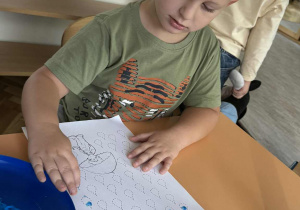 Zdjęcie przedstawia dzieci podczas malowania palcami