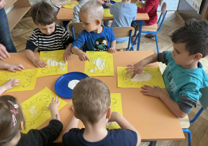 Zdjęcie przedstawia dzieci podczas malowania palcami