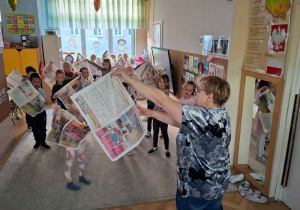 Zdjęcie przedstawia dzieci podczas zabaw z gazetami