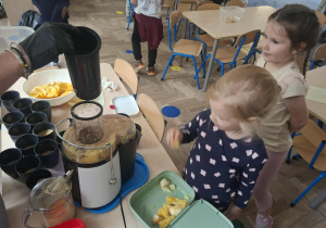 Zdjęcie przedstawia dzieci podczas robienia soku z owoców