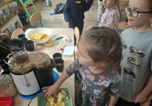 Zdjęcie przedstawia dzieci podczas robienia soku z owoców