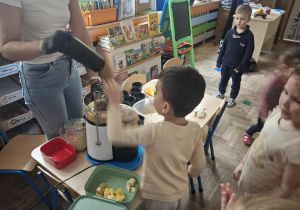 Zdjęcie przedstawia dzieci podczas robienia soku z owoców