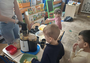 Zdjęcie przedstawia dzieci podczas robienia soku z owoców