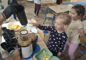 Zdjęcie przedstawia dzieci podczas robienia soku z owoców