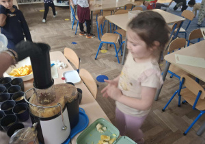 Zdjęcie przedstawia dzieci podczas robienia soku z owoców