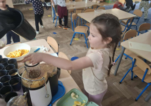 Zdjęcie przedstawia dzieci podczas robienia soku z owoców