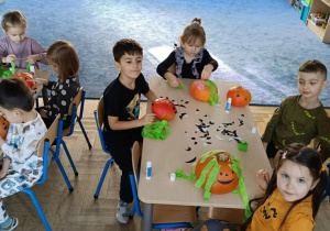 Zdjęcie przedstawia dzieci podczas dekorowania dyni