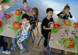 Zdjęcie przedstawia dzieci podczas dekorowania dyni