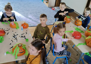 Zdjęcie przedstawia dzieci podczas dekorowania dyni