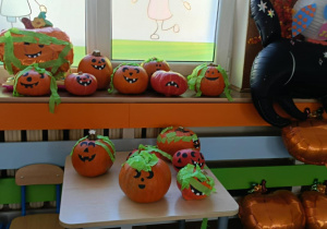 Zdjęcie przedstawia dzieci podczas dekorowania dyni