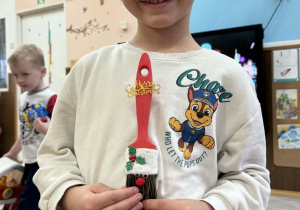 Zdjęcie przedstawia dzieci z wykonanym Mikołajem z pędzla