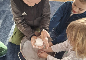 Zdjęcie przedstawia dzieci podczas zabaw ze śniegiem