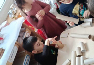 Zdjęcie przedstawia dzieci bawiące się materiałami z recyklingu