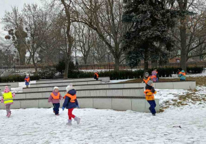 Zdjęcie przedstawia dzieci bawiące się na śniegu