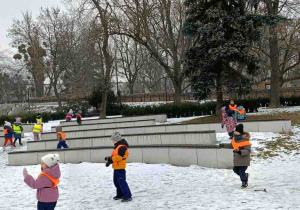 Zdjęcie przedstawia dzieci bawiące się na śniegu