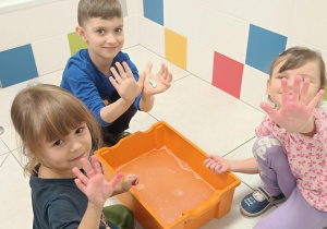 Zdjęcie przedstawia dzieci bawiące się w wodzie różnymi masami