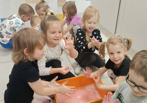 Zdjęcie przedstawia dzieci bawiące się w wodzie różnymi masami