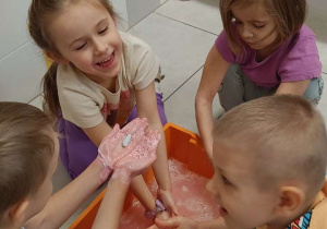 Zdjęcie przedstawia dzieci bawiące się w wodzie różnymi masami