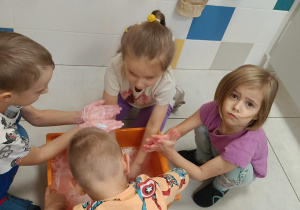 Zdjęcie przedstawia dzieci bawiące się w wodzie różnymi masami