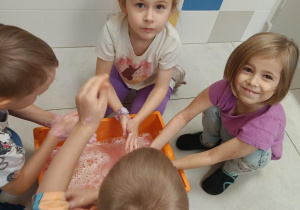 Zdjęcie przedstawia dzieci bawiące się w wodzie różnymi masami