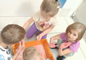 Zdjęcie przedstawia dzieci bawiące się w wodzie różnymi masami