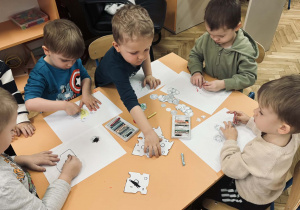 Zdjęcie przedstawia dzieci, które robią papierową pizze