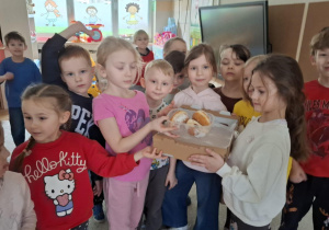 Zdjęcie przedstawia dzieci z pączkami