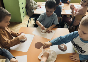 Zdjęcie przedstawia dzieci które wykonują papierowego pączka