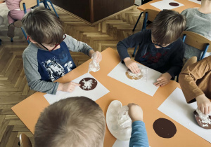 Zdjęcie przedstawia dzieci które wykonują papierowego pączka