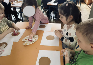 Zdjęcie przedstawia dzieci które wykonują papierowego pączka