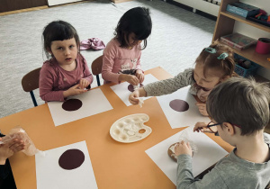 Zdjęcie przedstawia dzieci które wykonują papierowego pączka